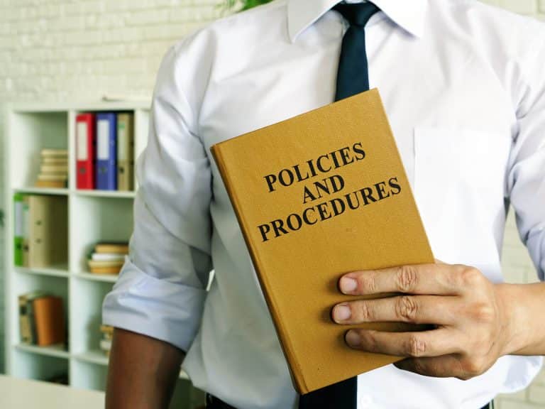 Man holding book that says Policies and Procedures