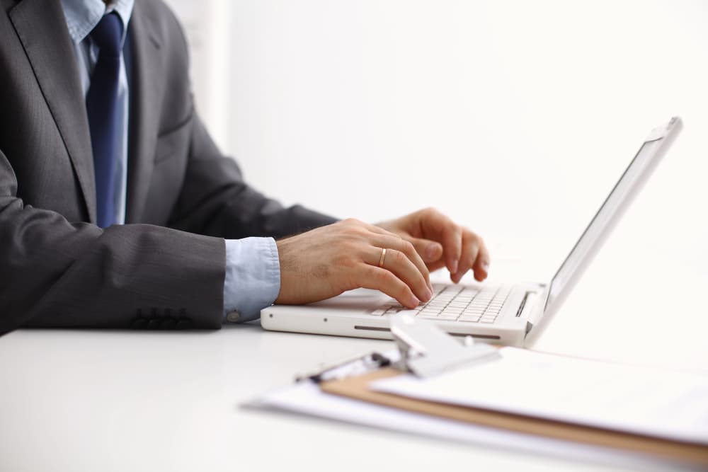 The DER or Designated Employer Representative - a man in a suit working on a laptop